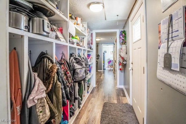 mudroom with attic access, baseboards, light wood-type flooring, and a textured ceiling