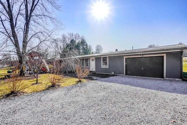 view of front of property featuring a garage, metal roof, and driveway