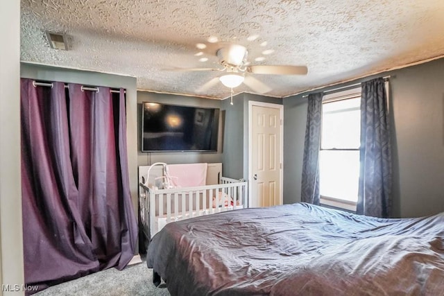 carpeted bedroom featuring visible vents, a textured ceiling, and ceiling fan