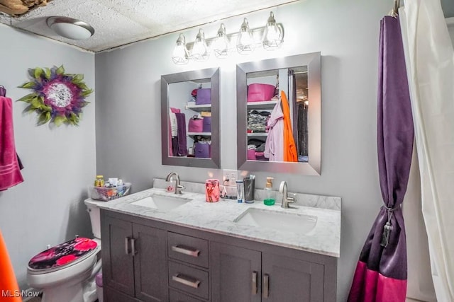 bathroom featuring double vanity, toilet, and a sink
