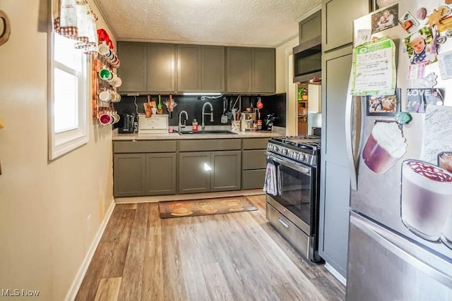 kitchen featuring a sink, light countertops, appliances with stainless steel finishes, a textured ceiling, and light wood-type flooring