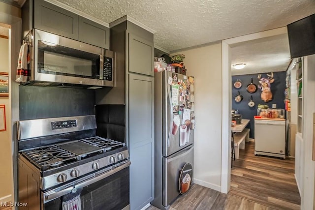 kitchen with wood finished floors, baseboards, appliances with stainless steel finishes, and a textured ceiling