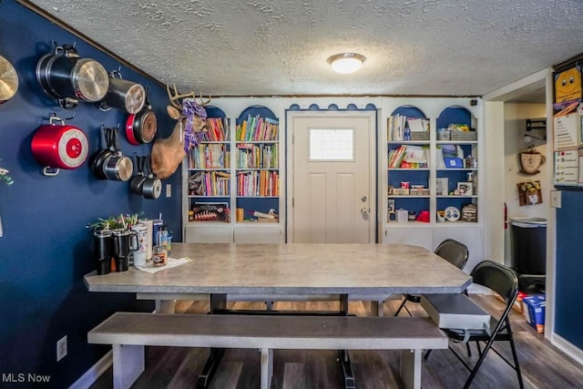 dining space featuring a textured ceiling, baseboards, and wood finished floors