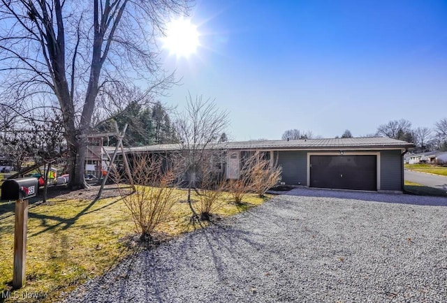 ranch-style house with gravel driveway, a garage, and metal roof