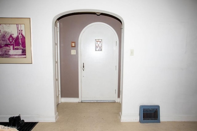 corridor with arched walkways, visible vents, and baseboards