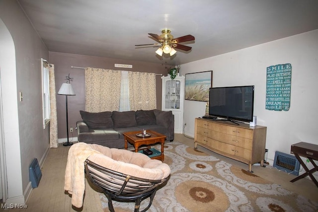 living room featuring light wood-style floors, arched walkways, and ceiling fan