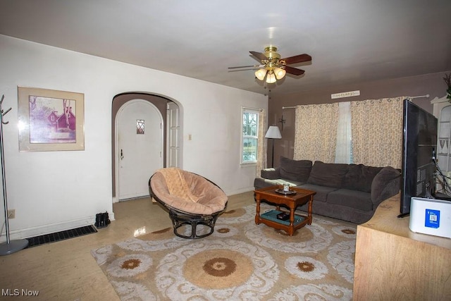 living area featuring arched walkways, visible vents, baseboards, and ceiling fan