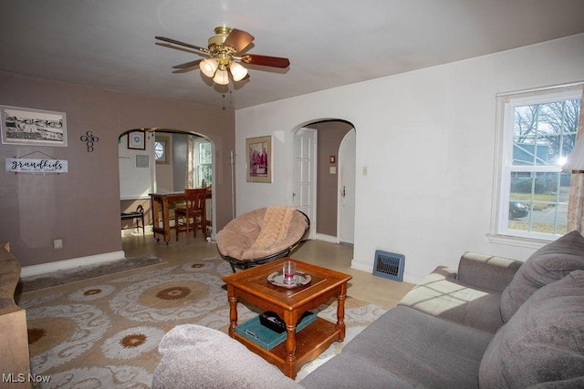 living room with visible vents, arched walkways, baseboards, and a ceiling fan