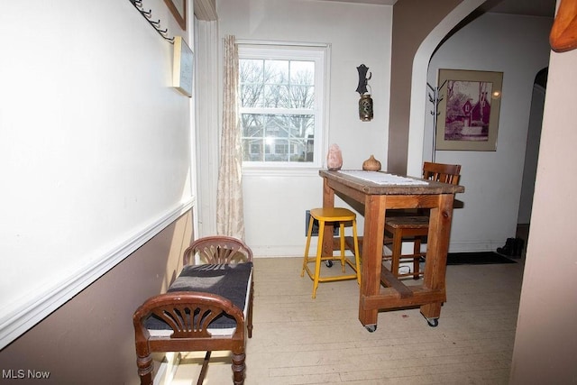 dining room featuring baseboards, arched walkways, and wood-type flooring