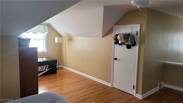 additional living space with visible vents, baseboards, lofted ceiling, and wood finished floors