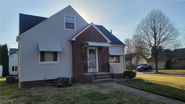 view of front of property featuring cooling unit, brick siding, roof with shingles, and a front lawn