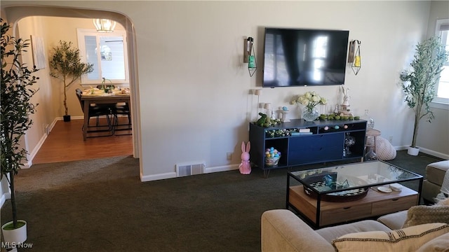 carpeted living area featuring arched walkways, visible vents, and baseboards