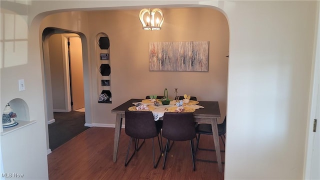 dining area with arched walkways, baseboards, and dark wood-style flooring