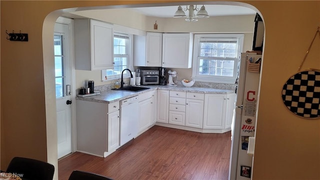 kitchen featuring a sink, white appliances, arched walkways, and light countertops