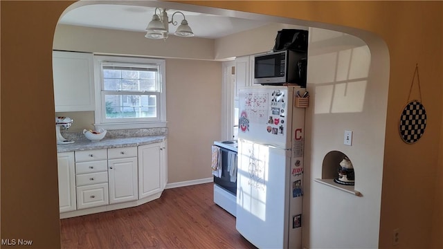 kitchen with light wood-style floors, white appliances, arched walkways, and light countertops