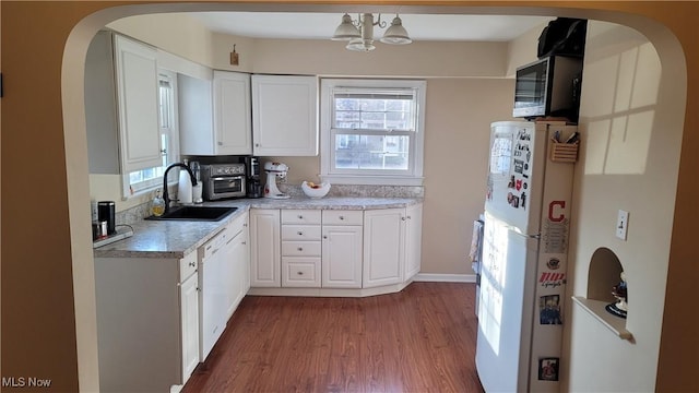 kitchen with white cabinetry, white appliances, light countertops, and a sink