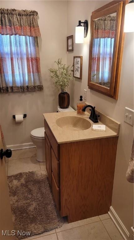 half bathroom featuring tile patterned flooring, toilet, vanity, and baseboards