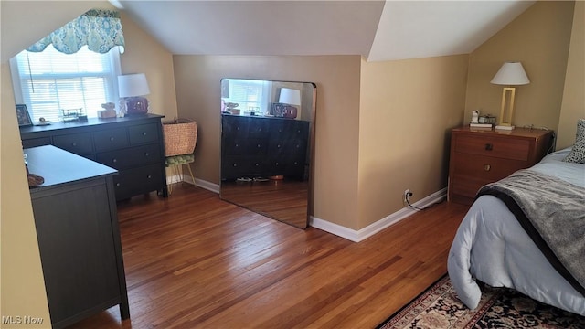 bedroom with baseboards, wood finished floors, and vaulted ceiling