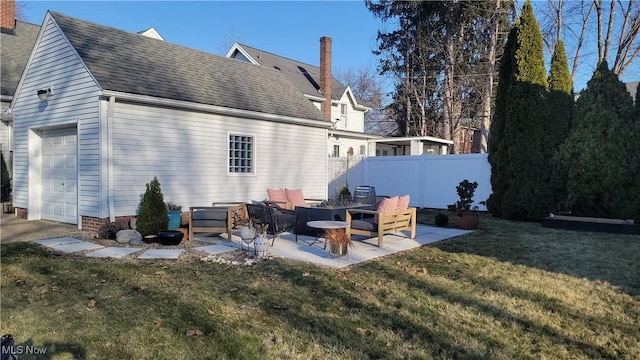 rear view of house with fence, roof with shingles, a lawn, a chimney, and a patio area