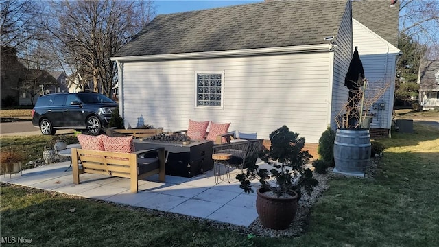 view of property exterior featuring a patio area, a lawn, roof with shingles, and a fire pit