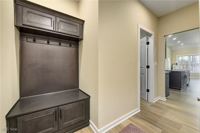 mudroom featuring light wood-style floors, baseboards, and a sink