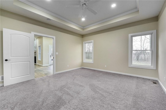 carpeted spare room with baseboards, a raised ceiling, and ornamental molding