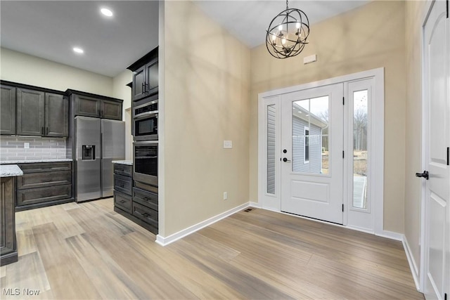 entrance foyer with recessed lighting, baseboards, an inviting chandelier, and light wood finished floors