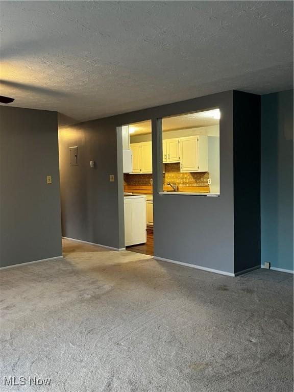 unfurnished living room featuring baseboards, carpet flooring, a textured ceiling, and a ceiling fan