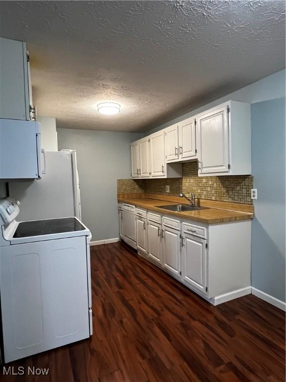 kitchen with dark wood-type flooring, a sink, white cabinetry, white appliances, and decorative backsplash