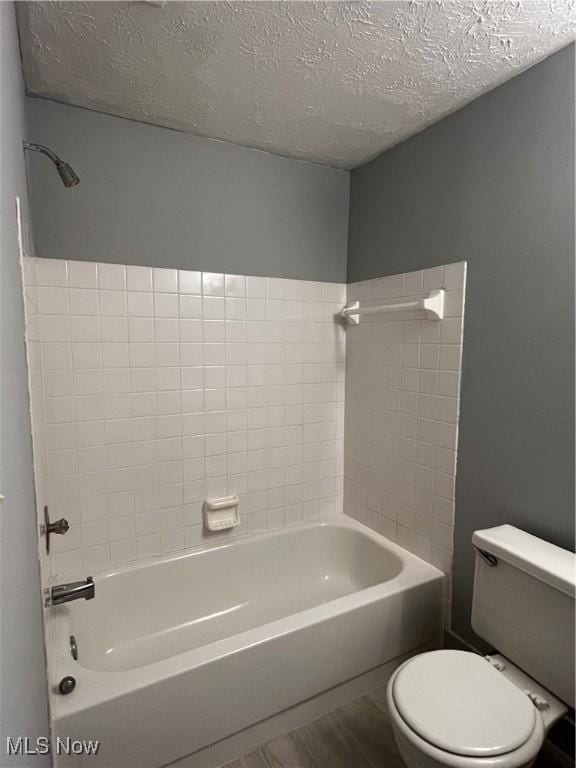 full bathroom featuring toilet, wood finished floors, shower / bathtub combination, and a textured ceiling