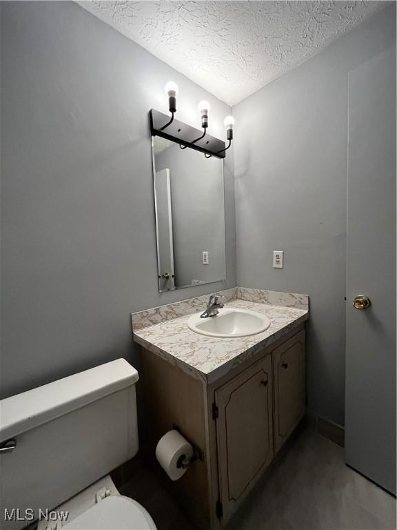 bathroom featuring vanity, toilet, and a textured ceiling