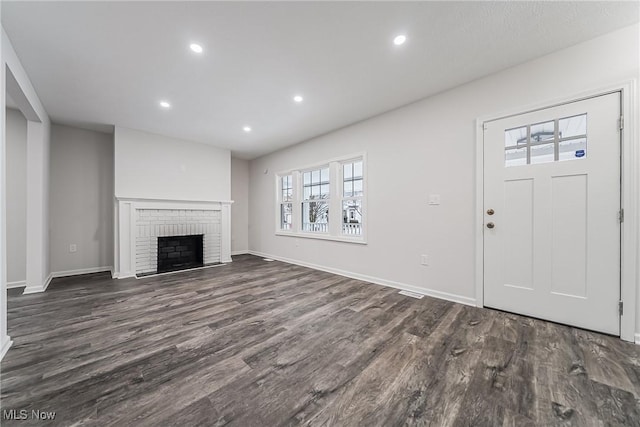 unfurnished living room with dark wood finished floors, recessed lighting, a fireplace, and baseboards