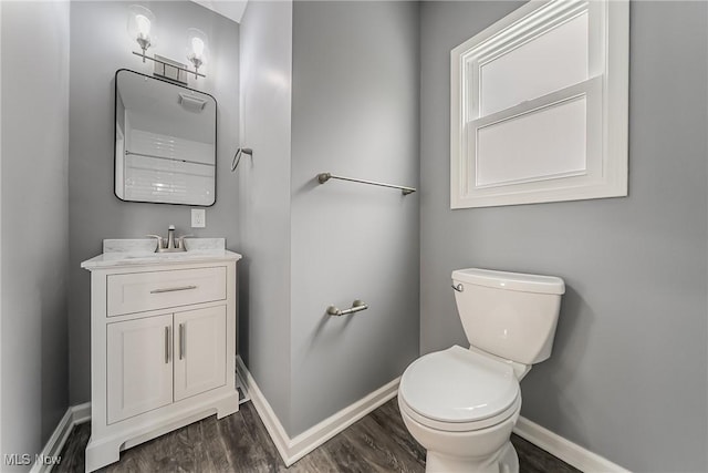 bathroom with baseboards, toilet, wood finished floors, and vanity