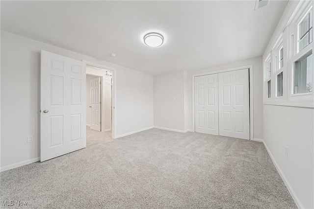 unfurnished bedroom featuring a closet, baseboards, and carpet floors