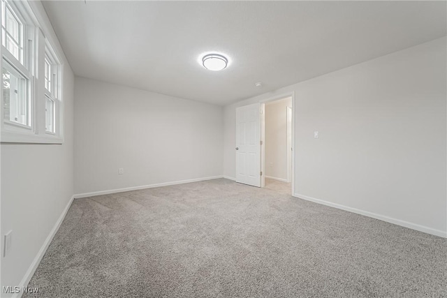 spare room with baseboards and carpet floors