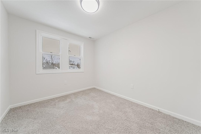 carpeted empty room featuring baseboards