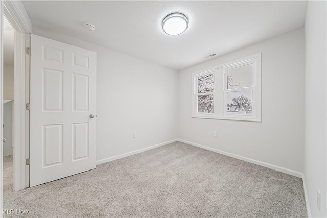 carpeted empty room with visible vents and baseboards