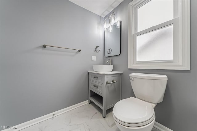 bathroom featuring baseboards, toilet, marble finish floor, and vanity