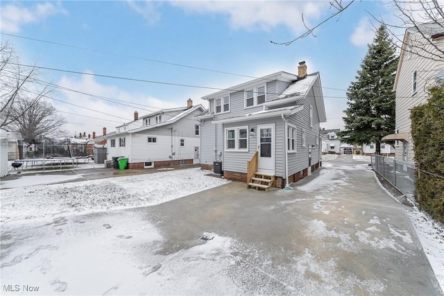 back of property with cooling unit, fence, a chimney, entry steps, and a trampoline