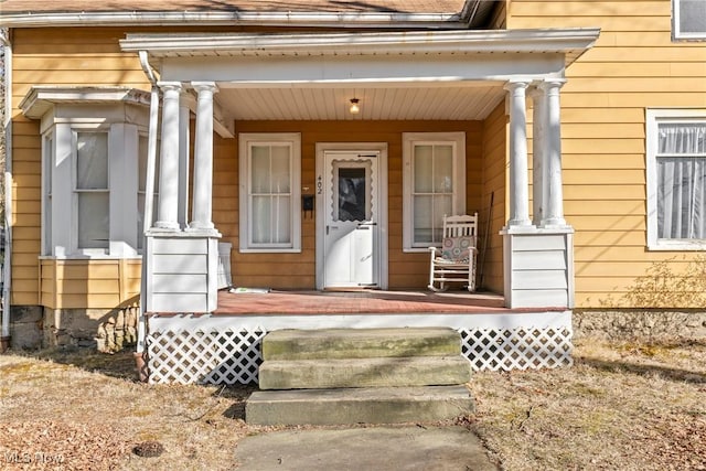 property entrance with covered porch and roof with shingles