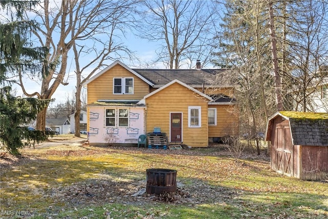 rear view of property featuring a yard, an outbuilding, a storage shed, and a chimney