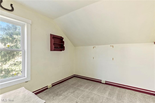 additional living space with vaulted ceiling, carpet flooring, a healthy amount of sunlight, and baseboards