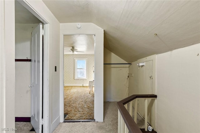 corridor featuring an upstairs landing, wallpapered walls, carpet, and vaulted ceiling