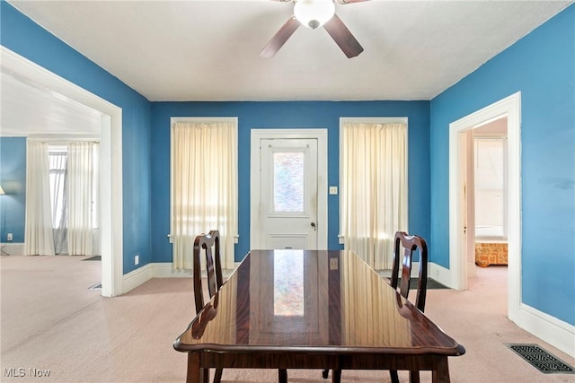 dining area with visible vents, light colored carpet, a ceiling fan, and baseboards