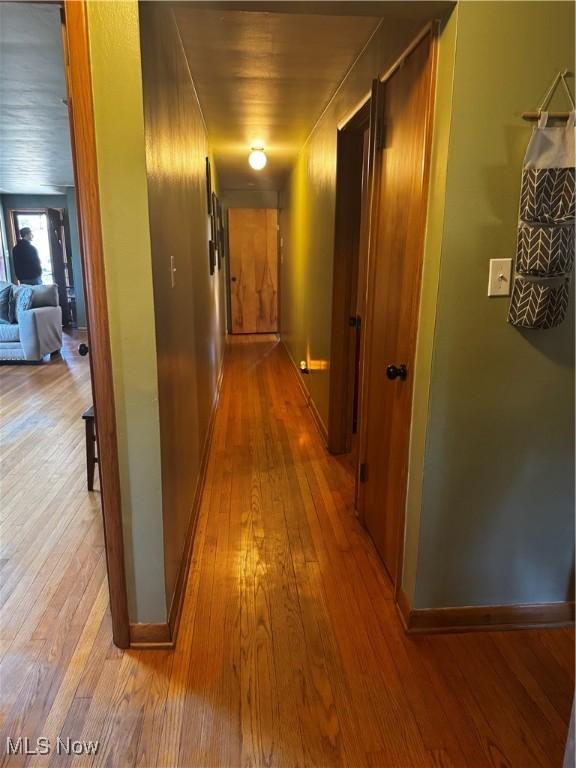 corridor with hardwood / wood-style floors and baseboards