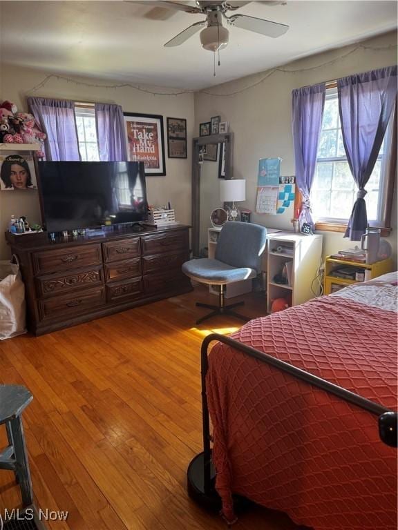 bedroom with ceiling fan, multiple windows, and wood finished floors