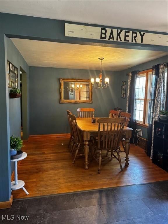 dining space with a notable chandelier, baseboards, and wood finished floors