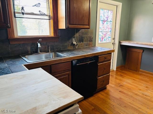 kitchen with a sink, tasteful backsplash, light wood finished floors, baseboards, and dishwasher