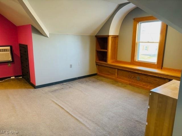 bonus room with lofted ceiling, baseboards, a wall mounted air conditioner, and light carpet