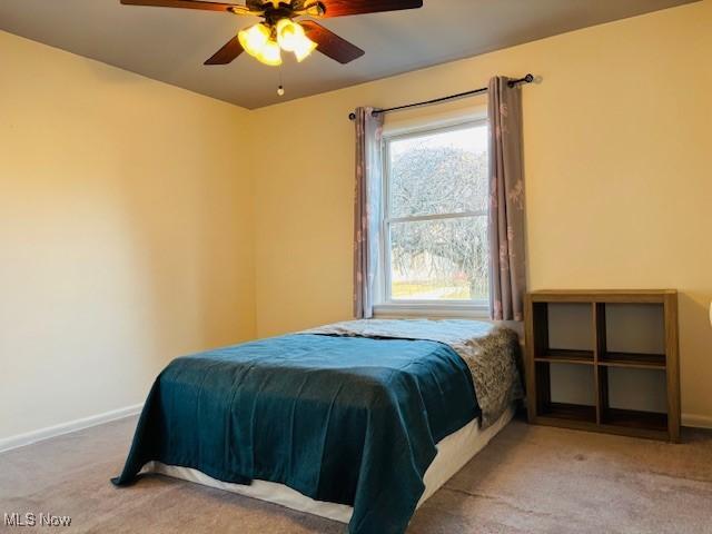 carpeted bedroom featuring baseboards and ceiling fan